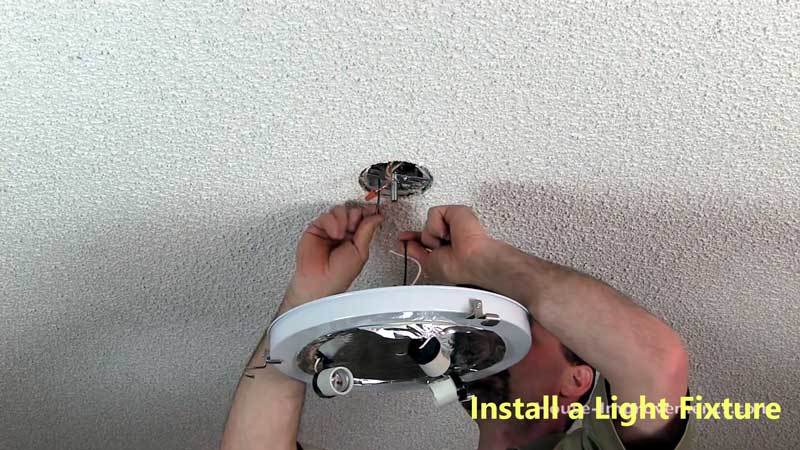 A person is installing a light fixture